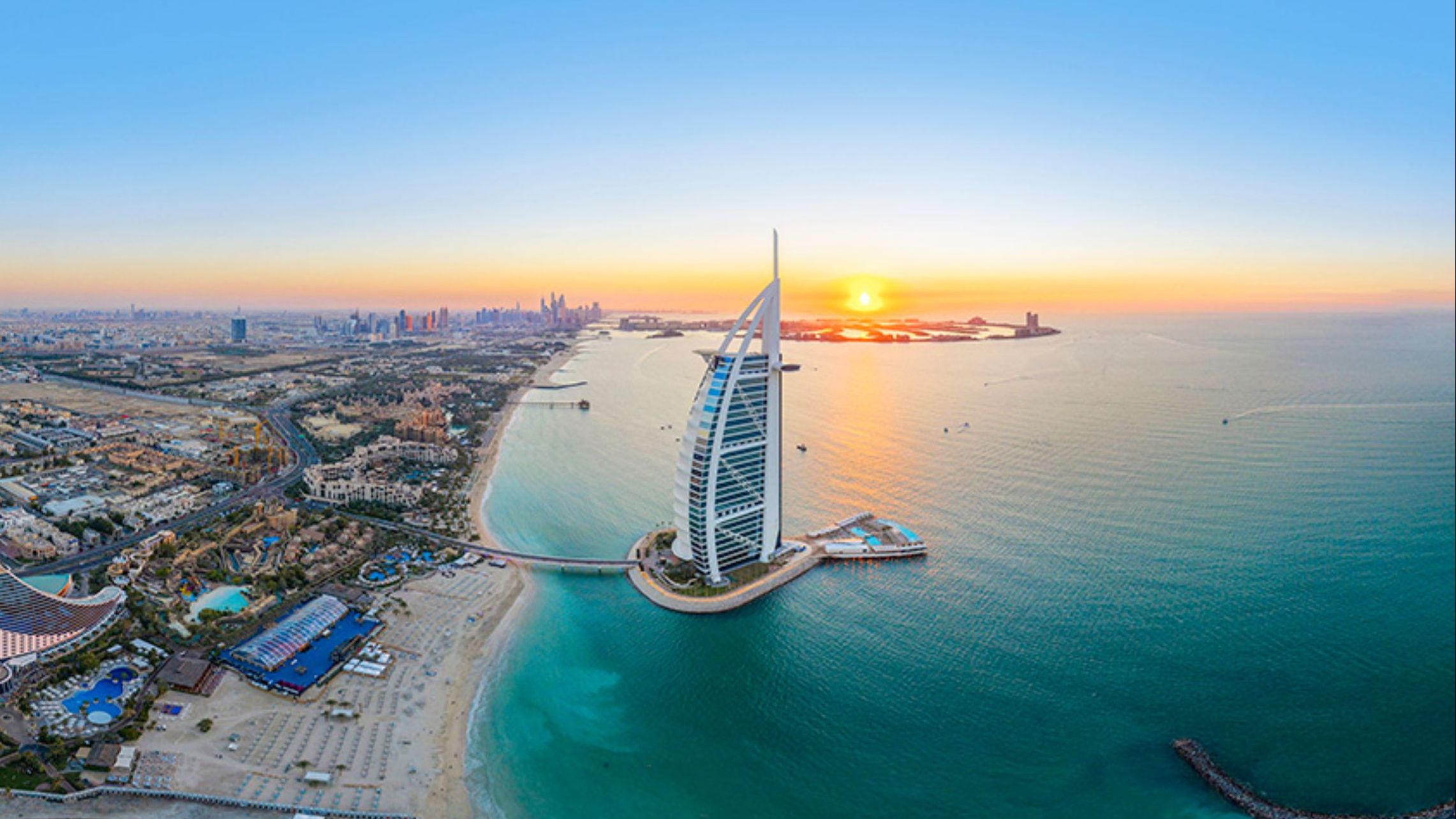 Luftaufnahme des Burj Al Arab in Dubai bei Sonnenuntergang, umgeben vom Meer und der Stadtküste | © MSC Cruises