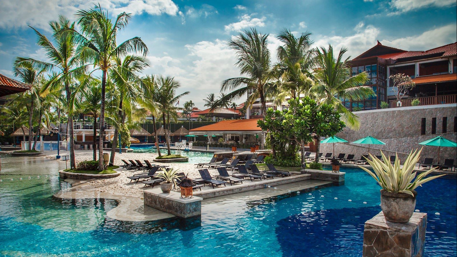 Hauptpool im Hard Rock Hotel Bali mit Palmen, Sonnenliegen und türkisblauem Wasser unter tropischem Himmel | © 2025 Hard Rock Cafe International (USA)